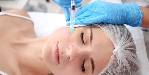 Una cosmetóloga realiza un procedimiento de rejuvenecimiento de la piel del rostro con plasma. 